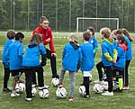 Tanja Baumann, Trainerin der Fußballfabrik, erklärt den Kindern der St. Rochus Schule die einzelnen Übungen.