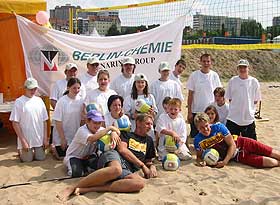 Das Volleyball-Team und die Trainer vor dem Plakat des Sponsors.